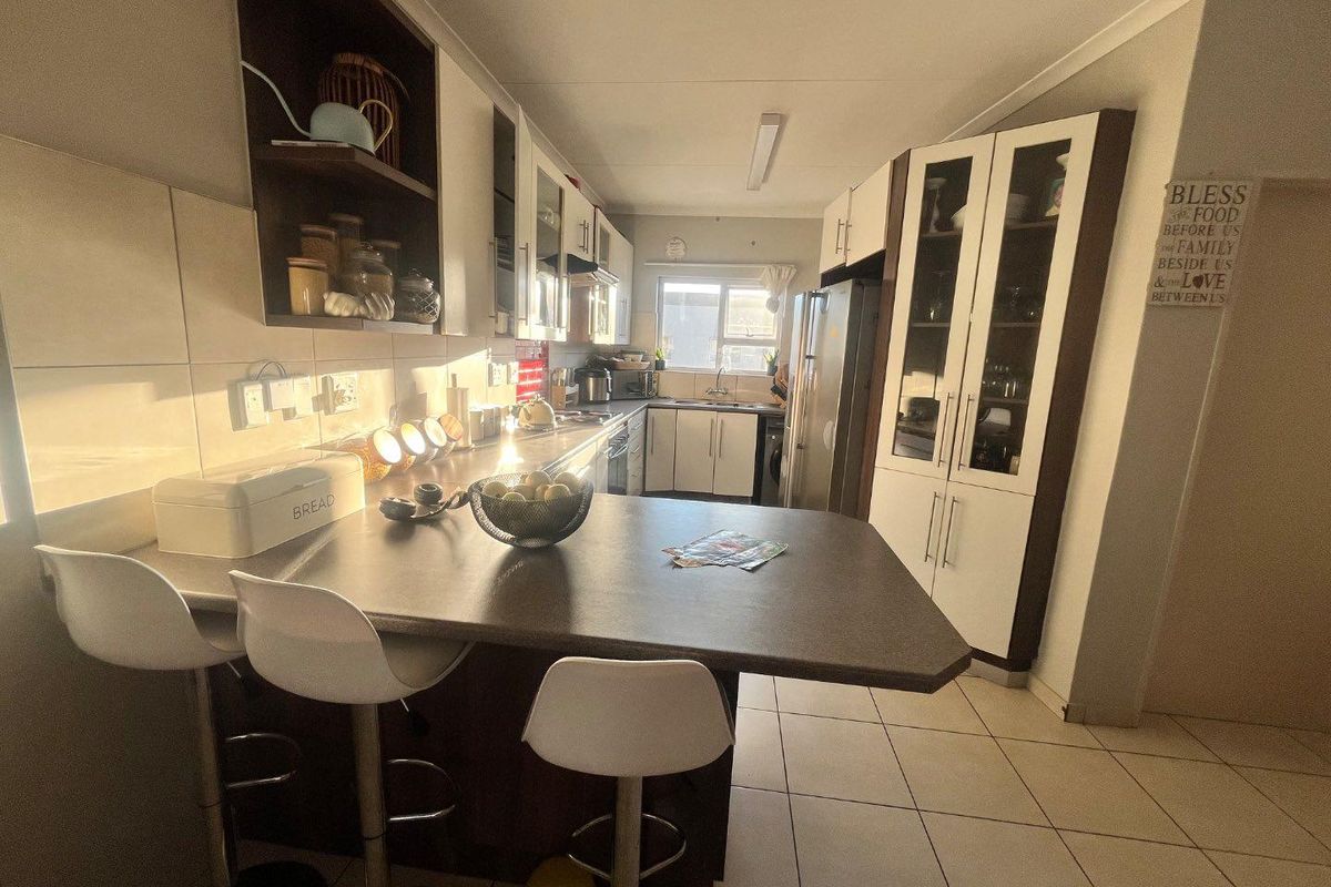 A functional kitchen featuring ample built-in cabinetry, a breakfast bar, tiled backsplash, and tiled flooring, offering a practical layout for daily use.