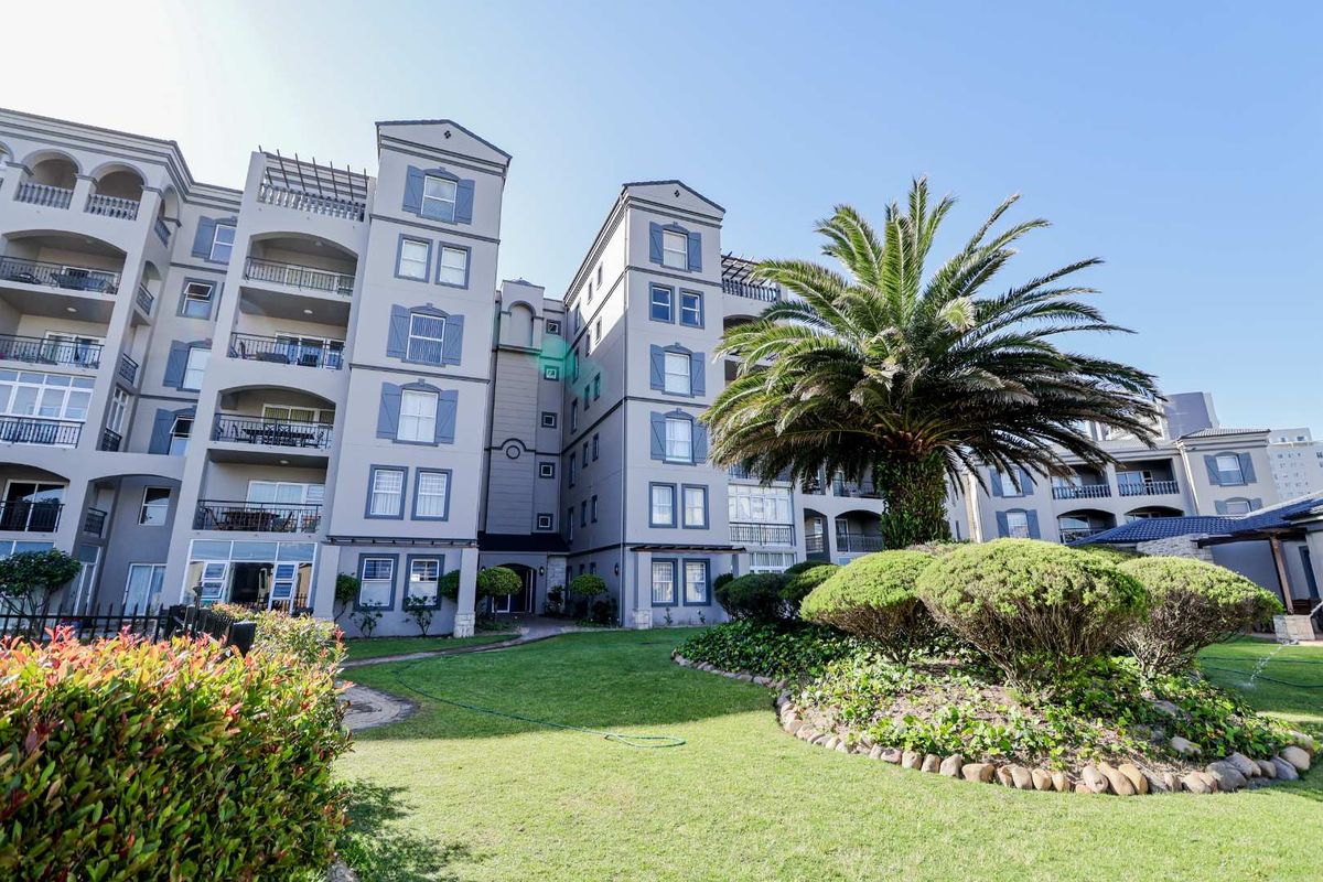 Exterior view of the apartment complex featuring landscaped gardens, manicured lawns, and multi-story building facades with balconies.