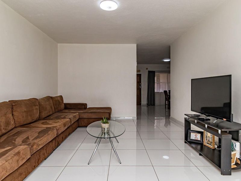 A spacious living room featuring neutral white walls and polished ceramic floor tiles, providing a clean and bright foundation for the home.