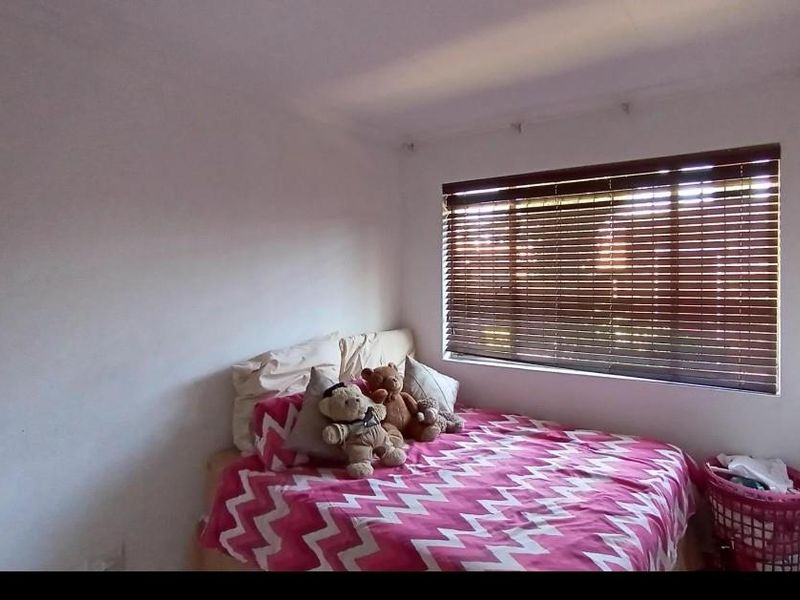 A standard bedroom featuring white walls and fitted venetian blinds, providing a neutral base for personalization.