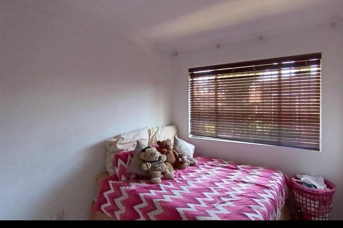 A standard bedroom featuring white walls and fitted venetian blinds, providing a neutral base for personalization.