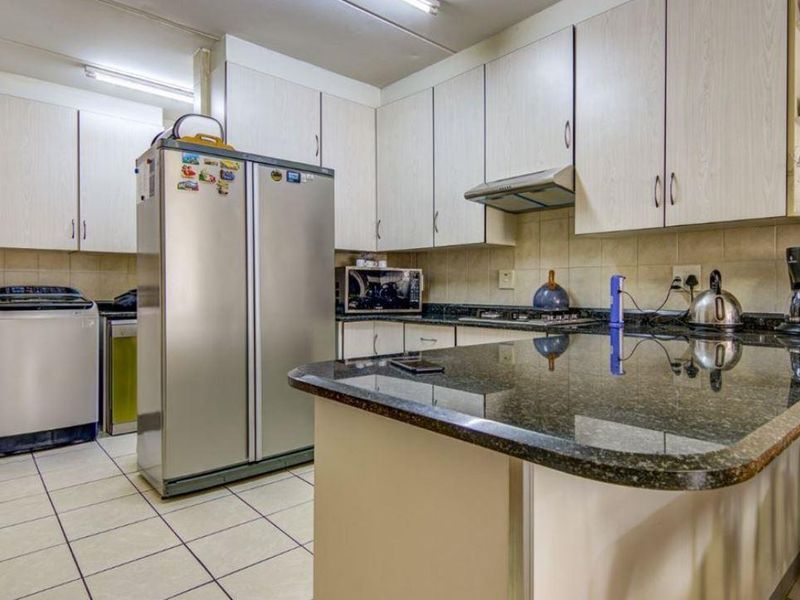A functional kitchen featuring light-toned cabinetry, granite countertops, a tiled backsplash, and integrated cooking appliances, offering a practical layout for daily use.