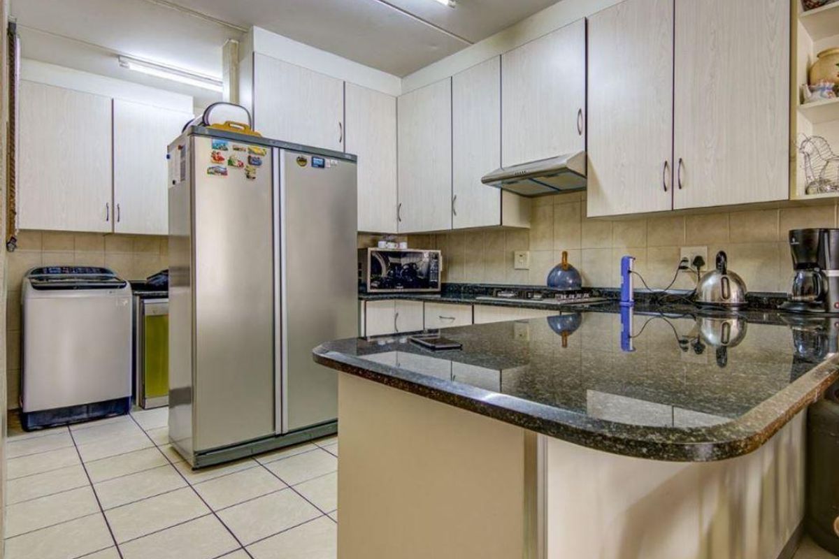 A functional kitchen featuring light-toned cabinetry, granite countertops, a tiled backsplash, and integrated cooking appliances, offering a practical layout for daily use.