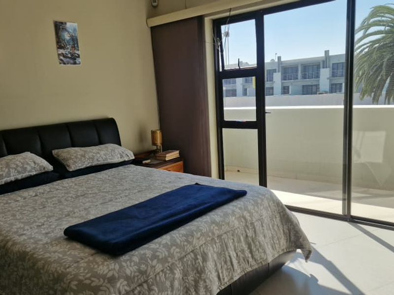A bedroom featuring tiled flooring and large sliding glass doors that provide direct access to a private balcony.