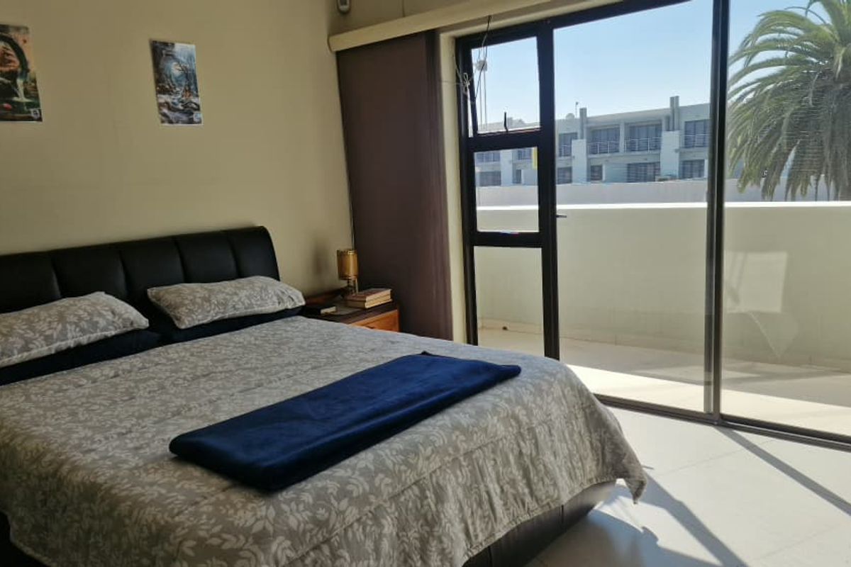 A bedroom featuring tiled flooring and large sliding glass doors that provide direct access to a private balcony.