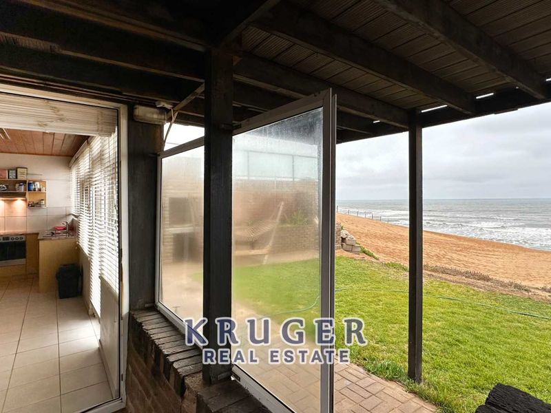 Covered patio area featuring a built-in braai, timber pergola, and direct access to the garden with scenic ocean views.