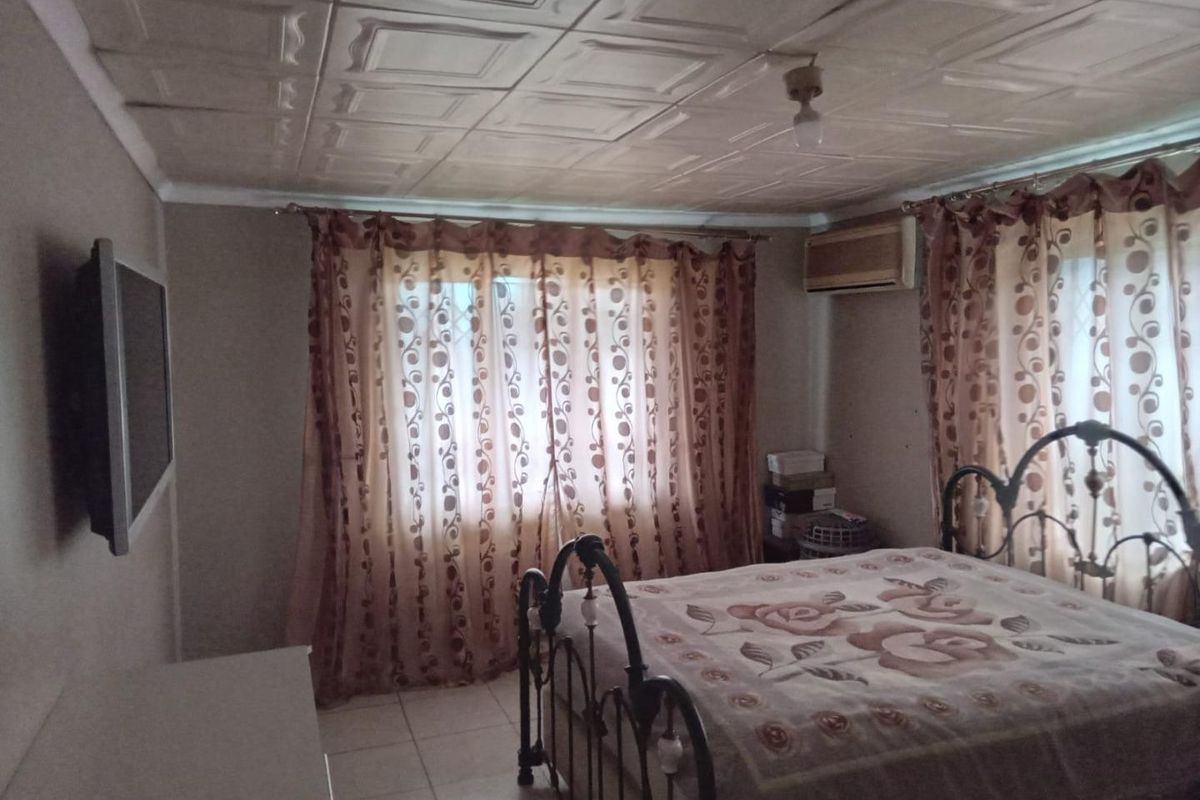 A bedroom featuring tiled flooring, a window-mounted air conditioning unit, and a decorative tiled ceiling.