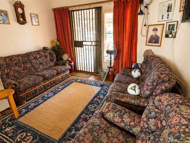 A living room featuring a traditional exposed thatch ceiling, tiled flooring, and a secure metal entrance gate.