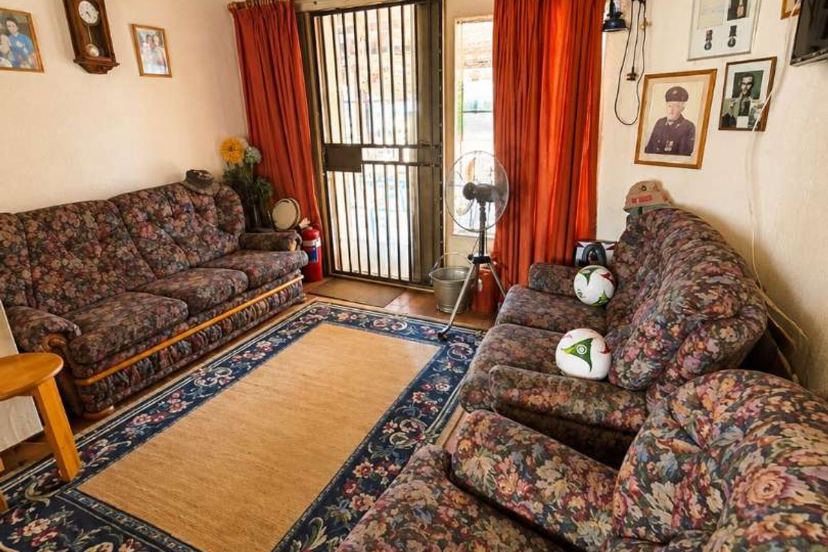 A living room featuring a traditional exposed thatch ceiling, tiled flooring, and a secure metal entrance gate.