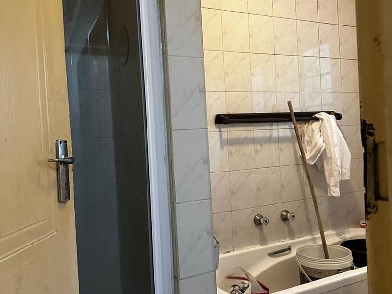 A dated bathroom featuring a shower enclosure and a bathtub with wall tiling, requiring cosmetic updates to improve its overall condition and appeal.