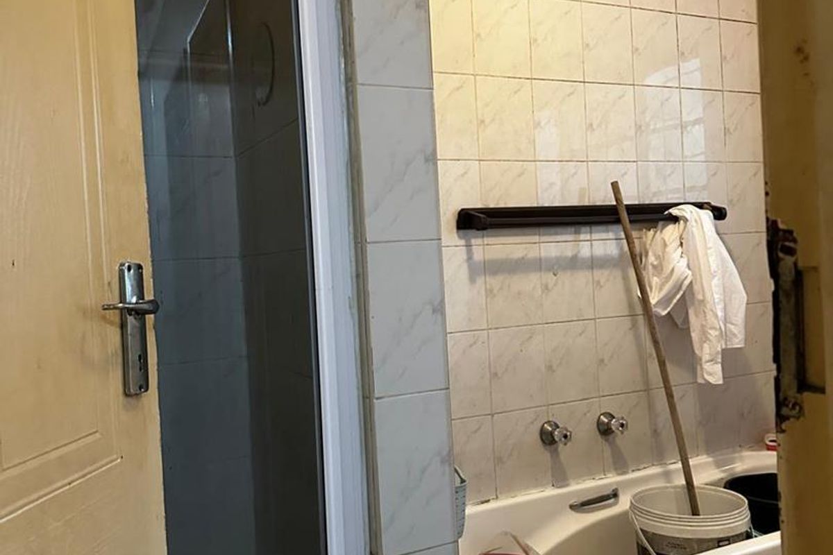 A dated bathroom featuring a shower enclosure and a bathtub with wall tiling, requiring cosmetic updates to improve its overall condition and appeal.
