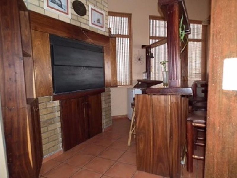 A dedicated bar area featuring a built-in timber counter, brick fireplace, and tiled flooring, offering a rustic entertainment space.