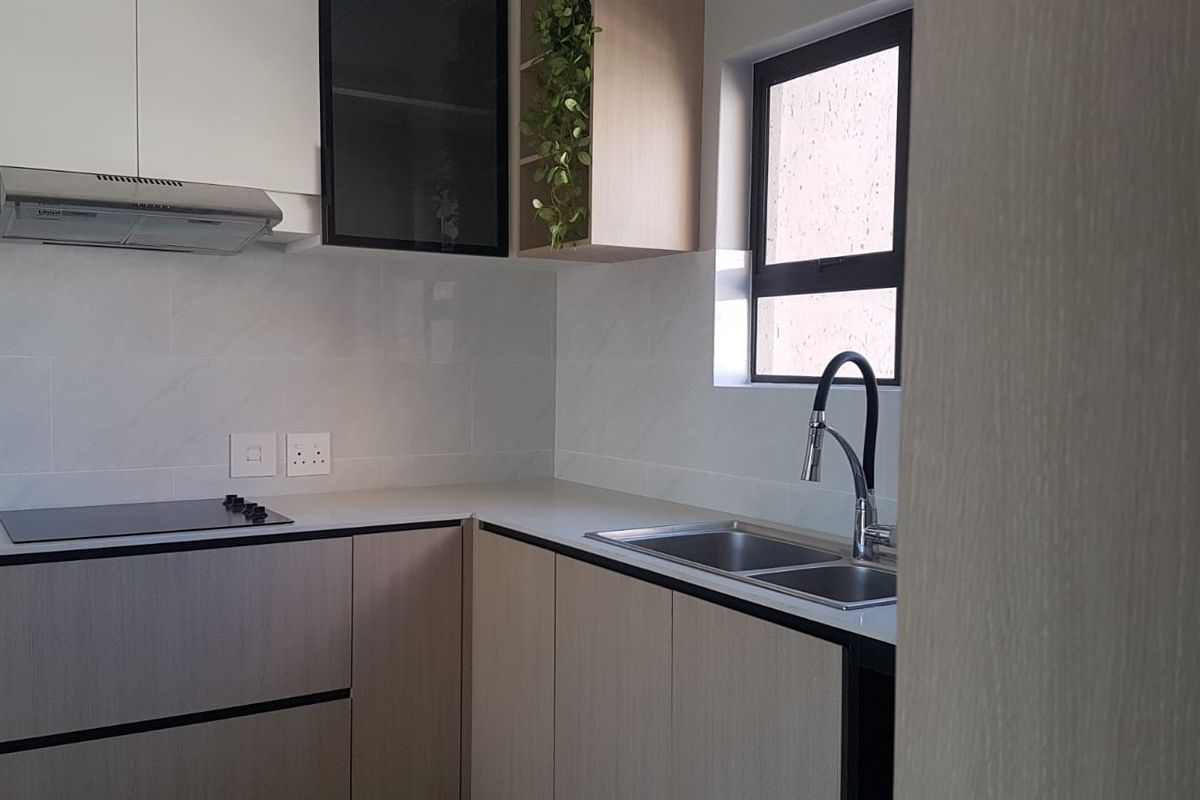 A modern, well-maintained kitchen featuring sleek cabinetry, stone countertops, a stainless steel double sink, and integrated cooking appliances.