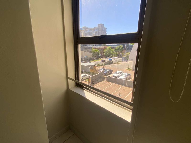 A view from a bedroom window overlooking a parking area and street.