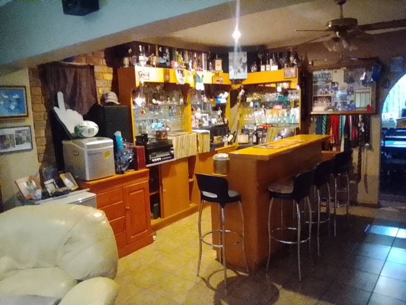 A dedicated home bar area featuring a built-in counter, cabinetry, and exposed brick wall detailing.