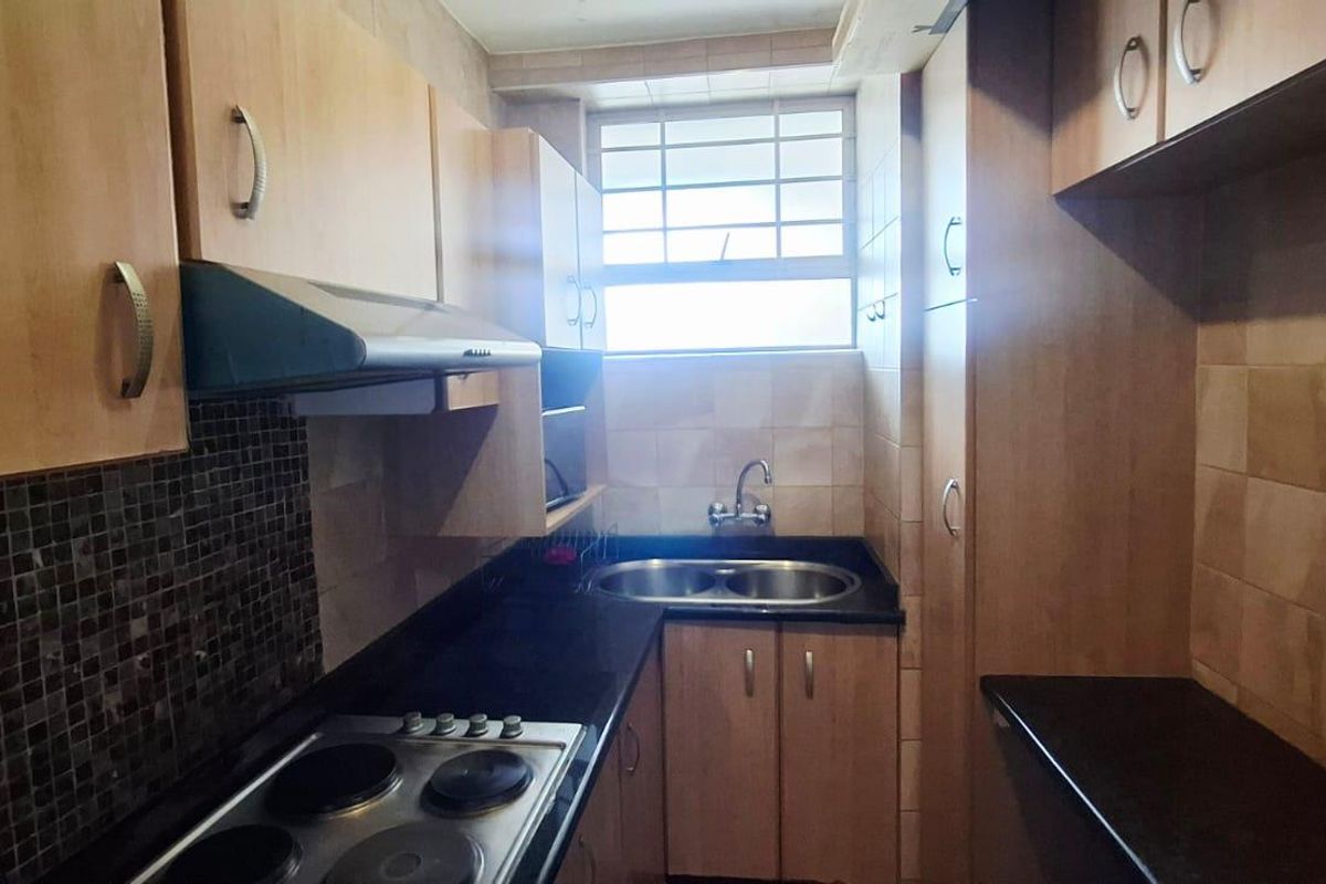 Compact kitchen featuring laminate cabinetry, granite countertops, a stainless steel double sink, electric hob, and extractor fan with tiled backsplash.