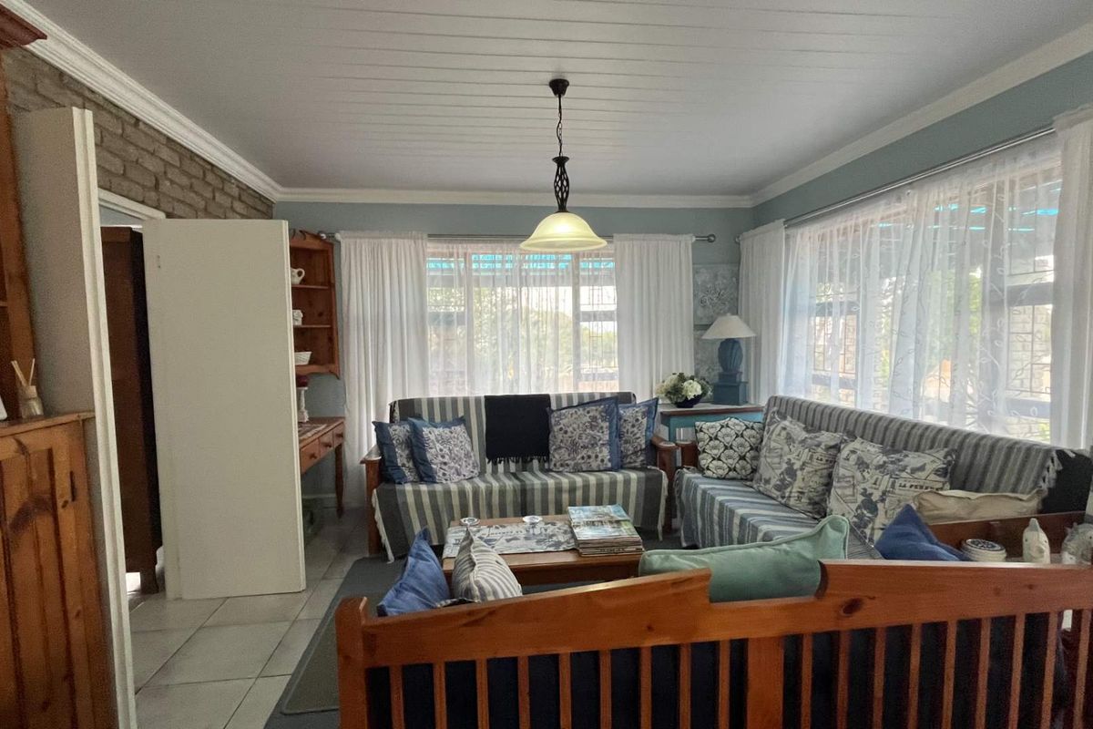 A comfortable living room featuring a brick accent wall, tiled flooring, and large windows that allow for ample natural light.