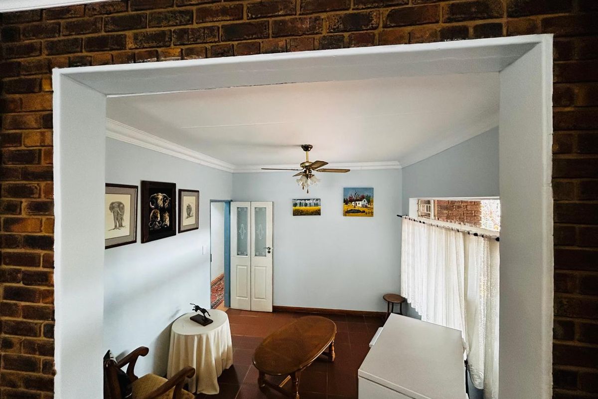 A living room featuring exposed brick accents, tiled flooring, and a ceiling fan, providing a classic and functional living space.