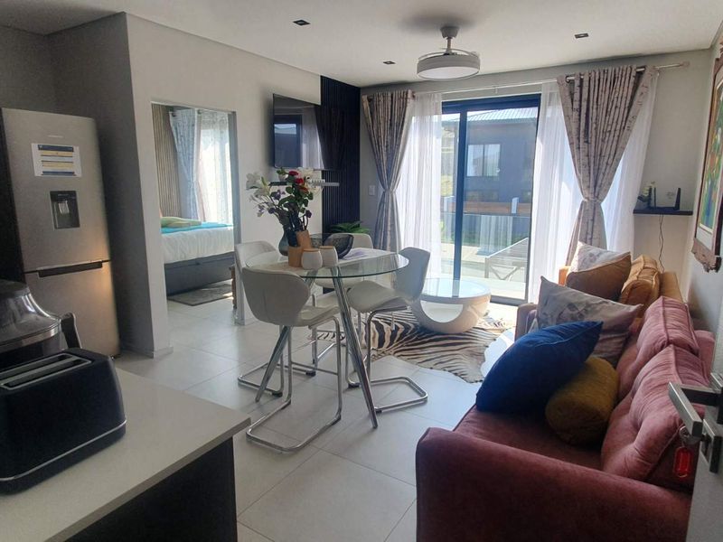 An open-plan living and dining area featuring tiled floors, recessed lighting, and a sliding glass door providing access to the outdoor space.