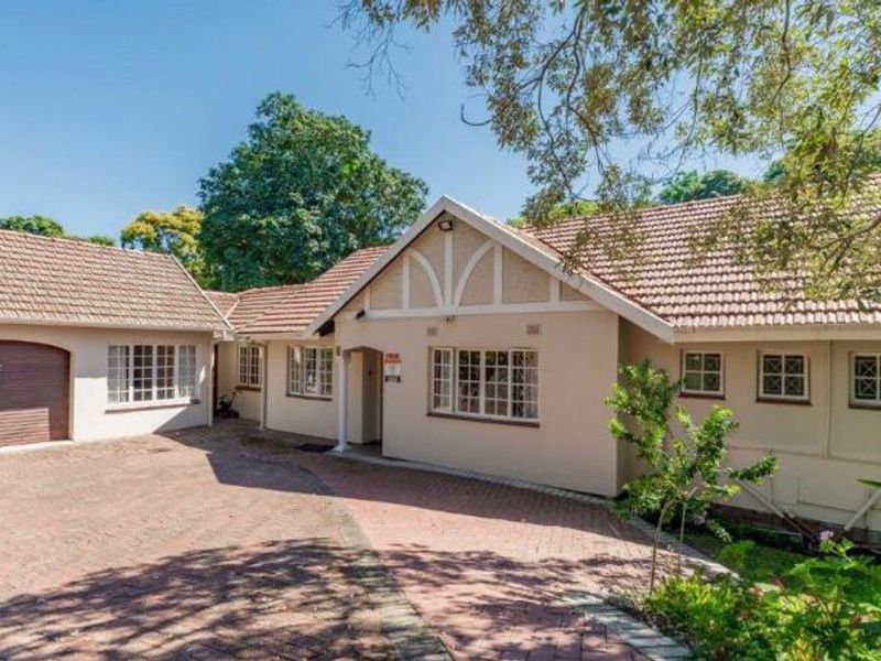 Front elevation of a single-story residence featuring a tiled roof, brick-paved driveway, and an integrated garage.