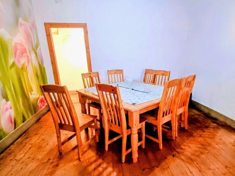 Dining room featuring natural timber flooring and a doorway leading to an adjacent space.