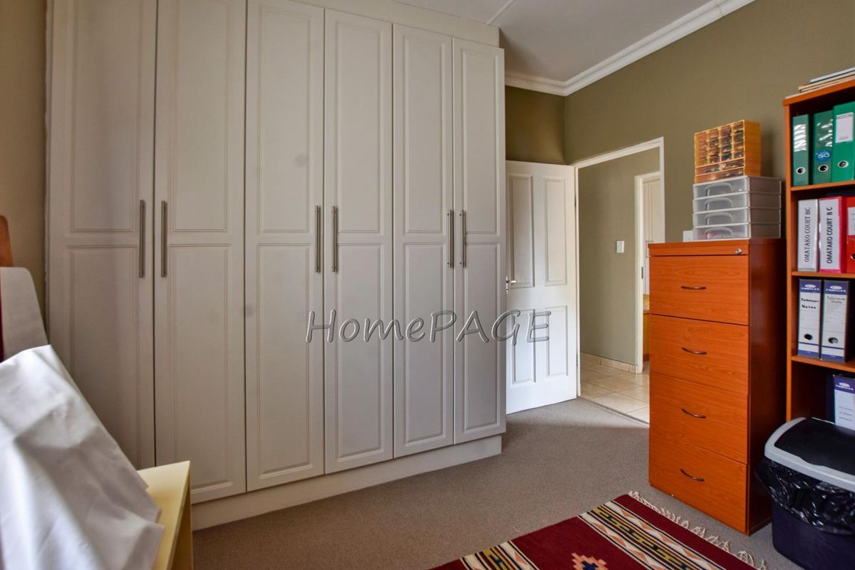 A bedroom featuring built-in floor-to-ceiling cabinetry with classic panel detailing and neutral carpeting.