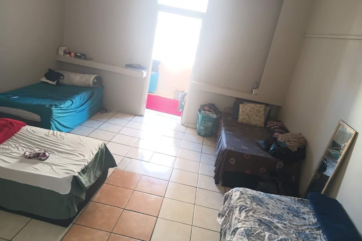 A spacious bedroom featuring tiled flooring, built-in shelving, and direct access to an outdoor balcony area.