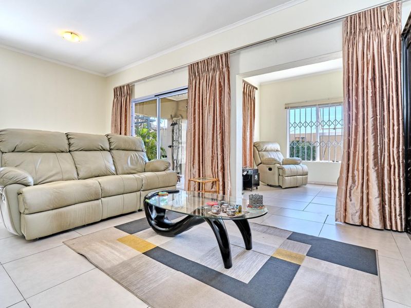 Spacious living area featuring neutral tiled flooring, large sliding glass doors providing natural light, and direct access to an adjoining sunroom or patio space.