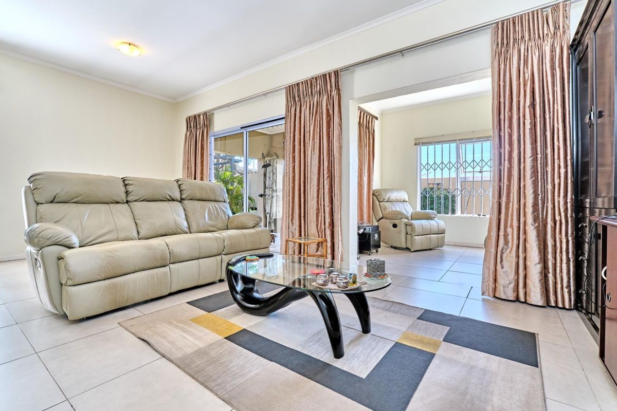 Spacious living area featuring neutral tiled flooring, large sliding glass doors providing natural light, and direct access to an adjoining sunroom or patio space.