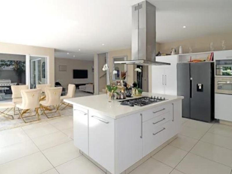 Spacious open-plan kitchen and dining area featuring a central island with gas hob, modern cabinetry, and seamless access to the outdoor patio.