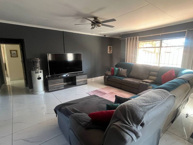 Spacious living room featuring large format floor tiles, a ceiling fan, and dark accent walls, providing a contemporary foundation for the home.
