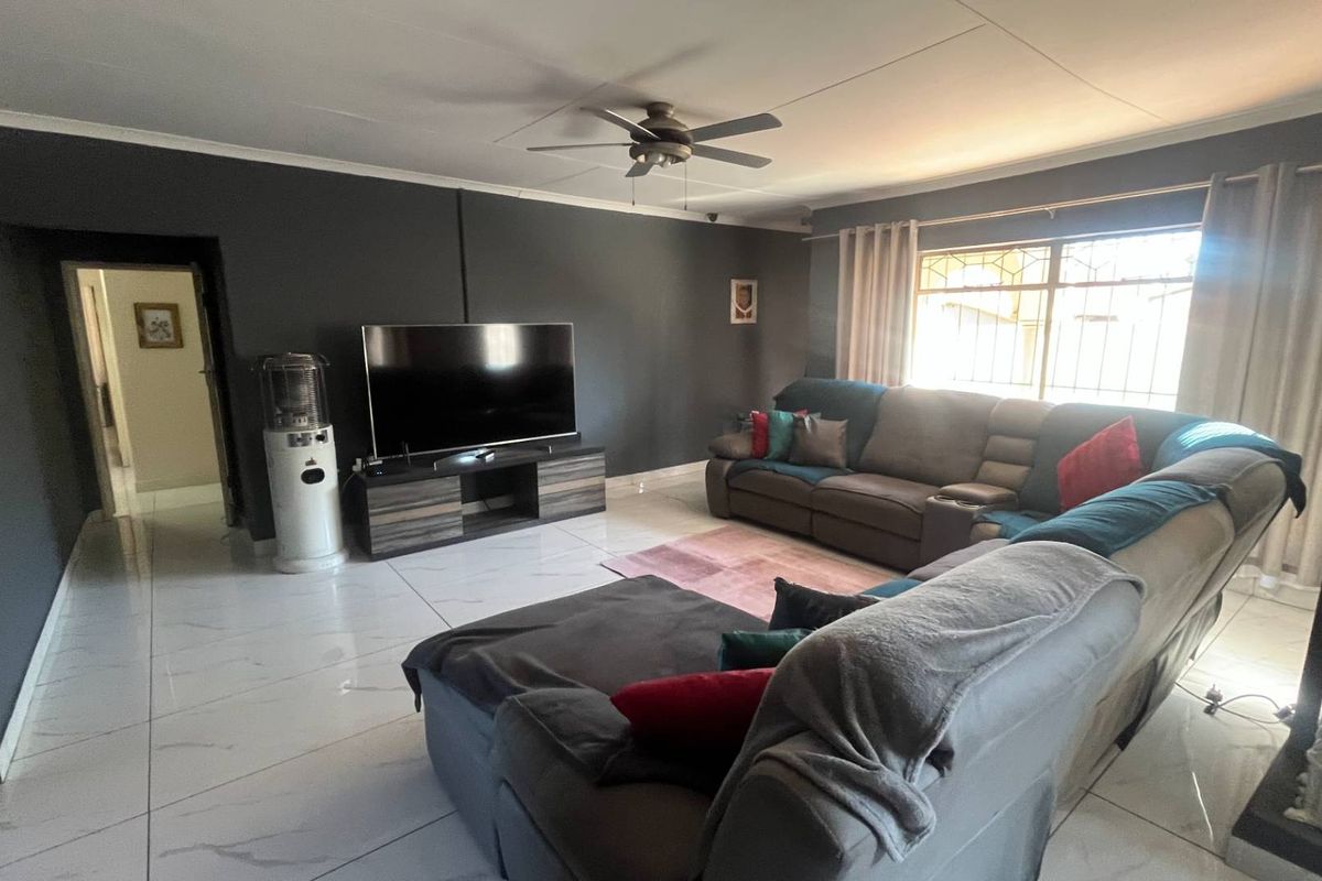 Spacious living room featuring large format floor tiles, a ceiling fan, and dark accent walls, providing a contemporary foundation for the home.