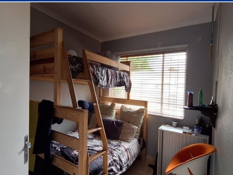A compact bedroom featuring tiled flooring and a window with fitted venetian blinds.