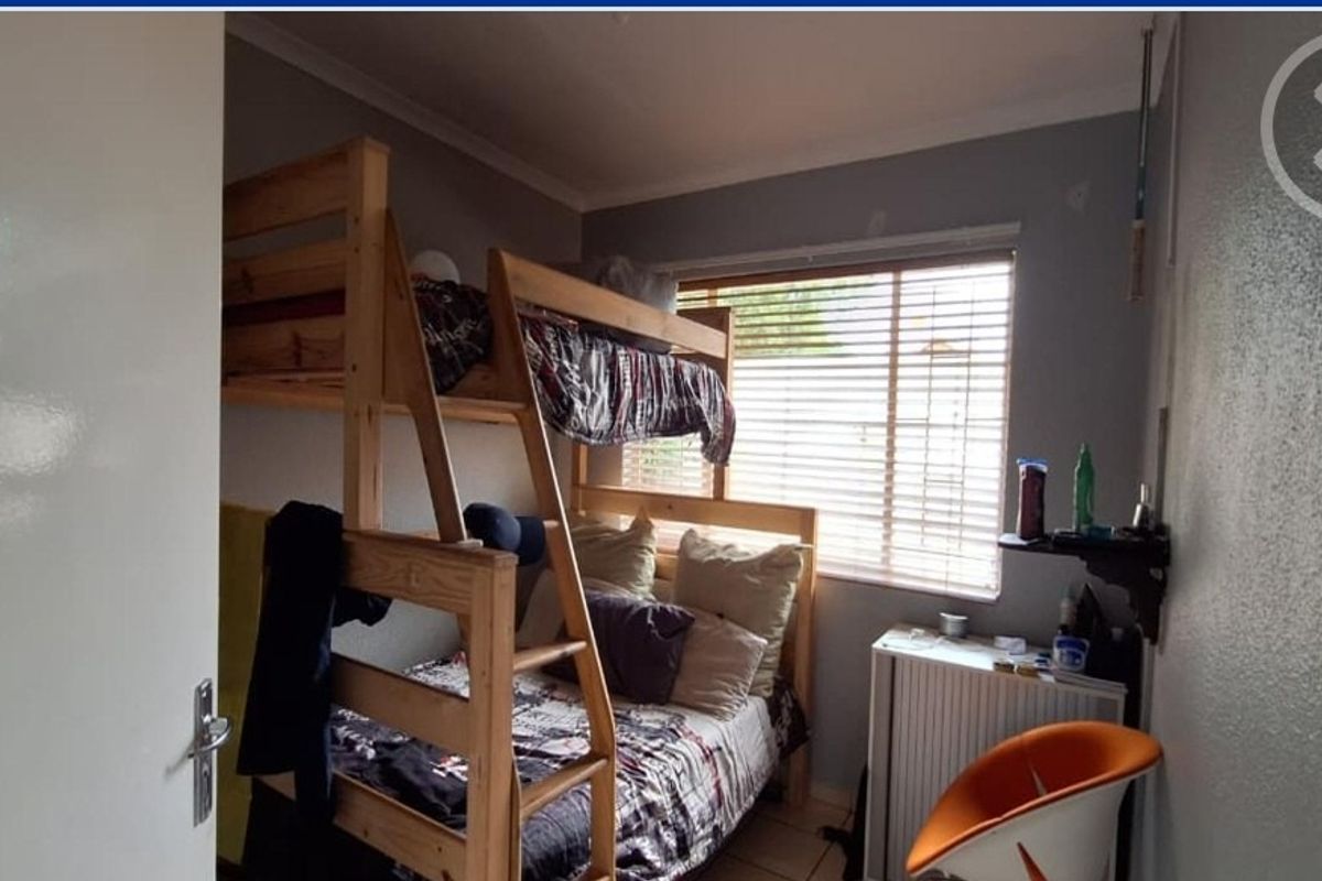 A compact bedroom featuring tiled flooring and a window with fitted venetian blinds.