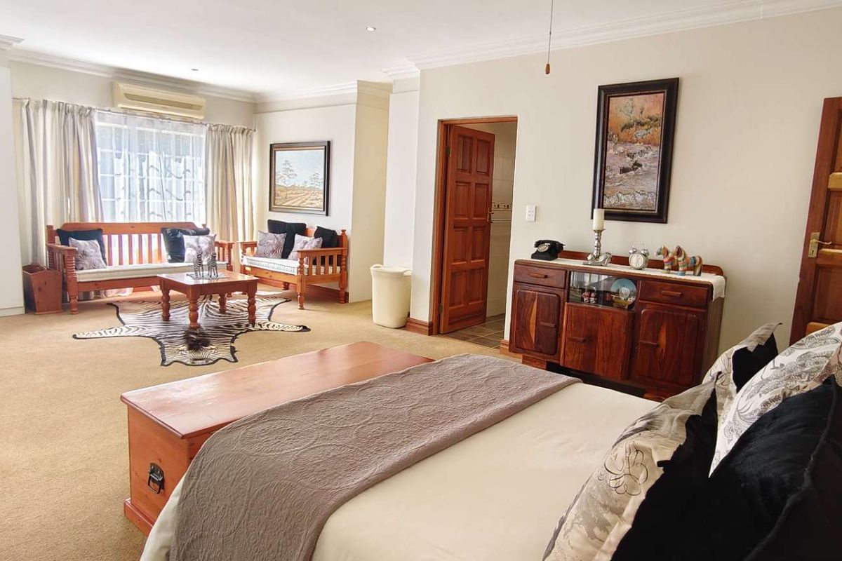 Spacious bedroom featuring built-in cupboards, carpeted flooring, and an en-suite bathroom access, offering a comfortable and functional living space.