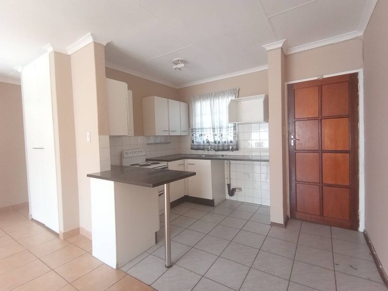 A functional kitchen featuring built-in cabinetry, a breakfast bar, tiled splashbacks, and a freestanding stove, offering a clean and practical layout.