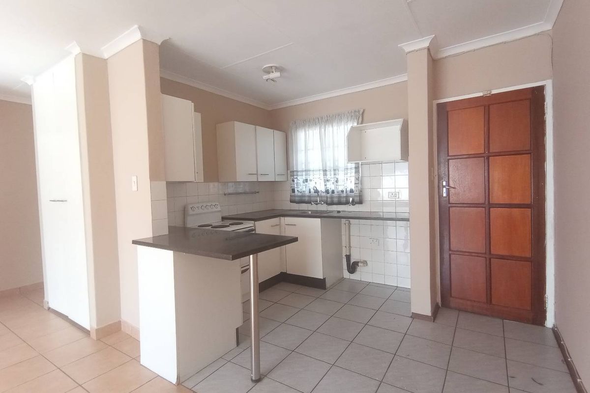 A functional kitchen featuring built-in cabinetry, a breakfast bar, tiled splashbacks, and a freestanding stove, offering a clean and practical layout.