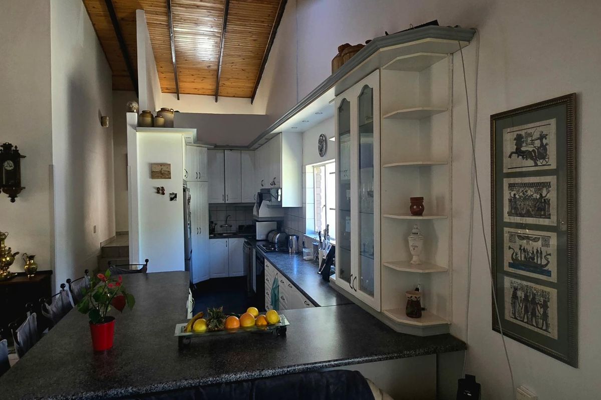 A functional kitchen featuring a long breakfast bar, built-in cabinetry, and a high vaulted timber ceiling, creating an open and airy atmosphere.