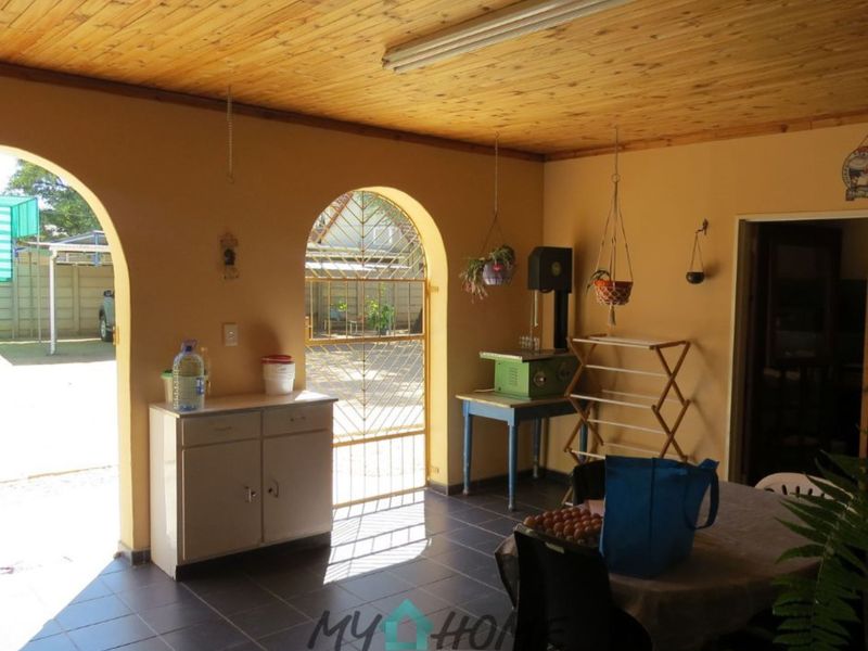 A covered patio area featuring arched doorways, tiled flooring, and a timber-clad ceiling, providing direct access to the rear garden.