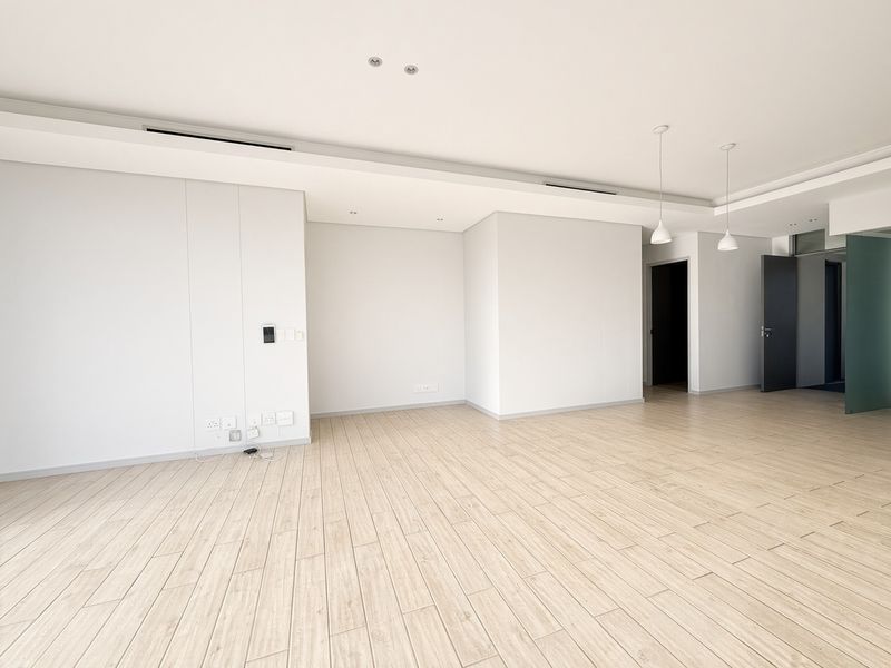 A bright, modern, and spacious open-plan living area featuring neutral wood-look tile flooring, recessed ceiling lighting, and integrated ducted air conditioning.