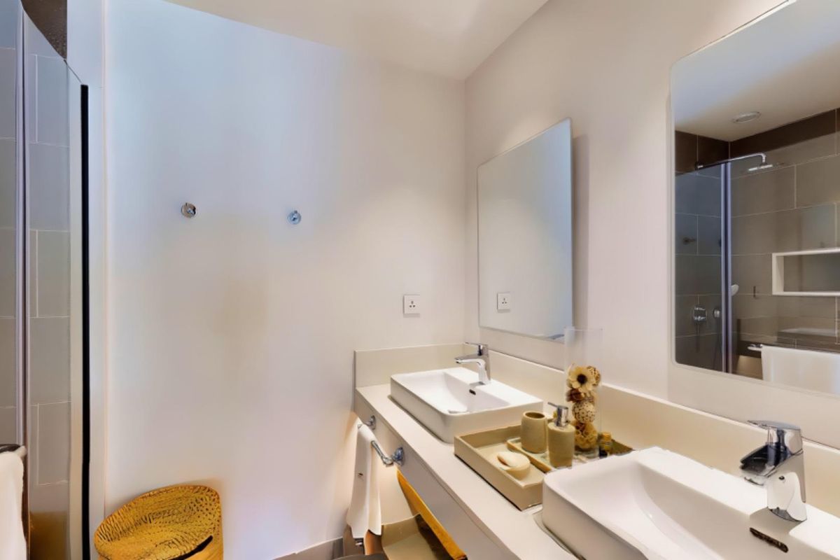 Modern bathroom featuring a double vanity with vessel sinks, wall-mounted mirrors, and a glass-enclosed shower with tiled walls.