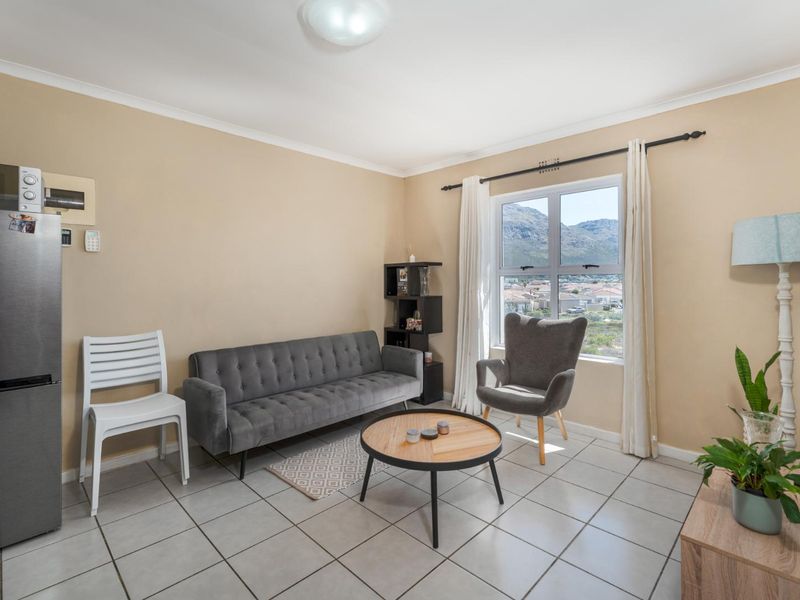 A bright living room featuring tiled flooring and a window offering scenic mountain views, providing a comfortable and functional living space.