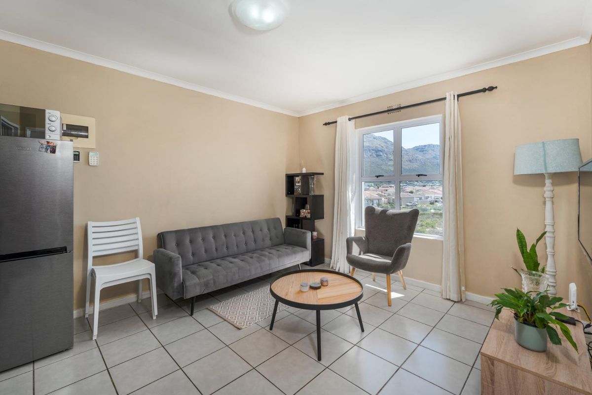 A bright living room featuring tiled flooring and a window offering scenic mountain views, providing a comfortable and functional living space.
