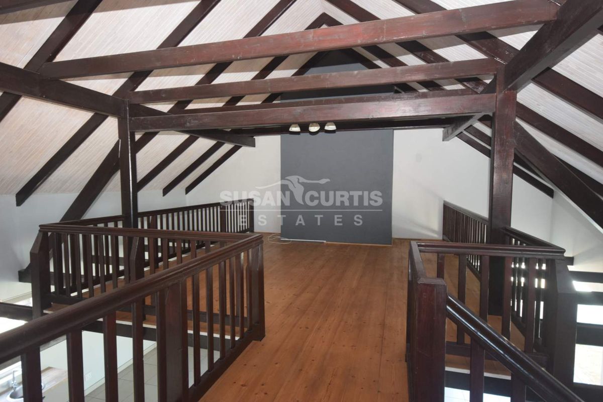 Spacious loft-style living area featuring exposed timber roof trusses, vaulted ceilings, and warm timber flooring with a protective balustrade.