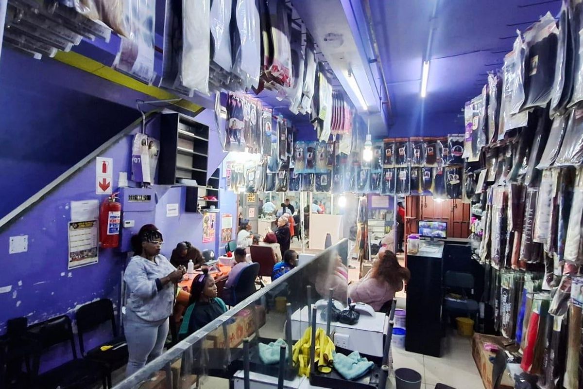 Interior view of a commercial retail space featuring wall-mounted product displays, fluorescent lighting, and basic utility infrastructure.