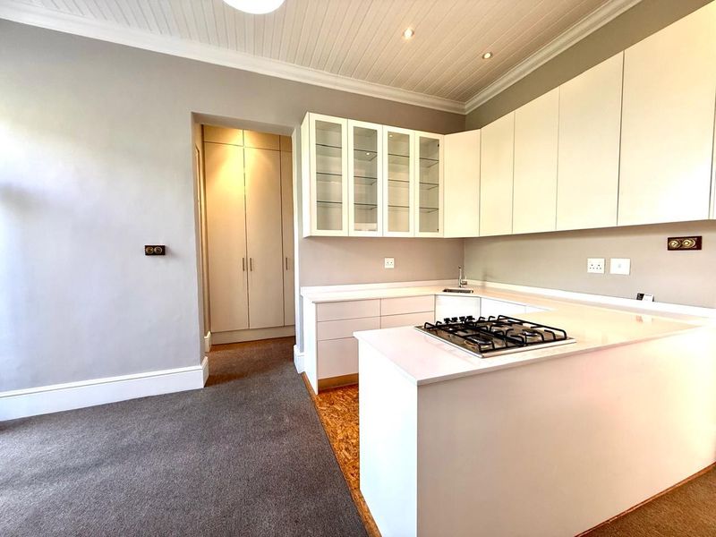 Modern kitchen featuring white cabinetry, stone countertops, a gas hob, and integrated sink, complemented by a tongue and groove ceiling and built-in pantry storage.