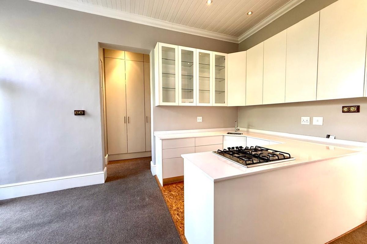 Modern kitchen featuring white cabinetry, stone countertops, a gas hob, and integrated sink, complemented by a tongue and groove ceiling and built-in pantry storage.