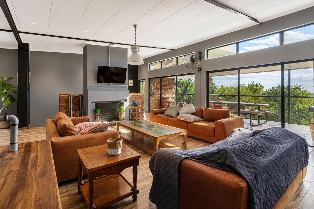 Spacious living room featuring a fireplace, exposed brick accents, and large sliding glass doors that open onto a patio with scenic views.