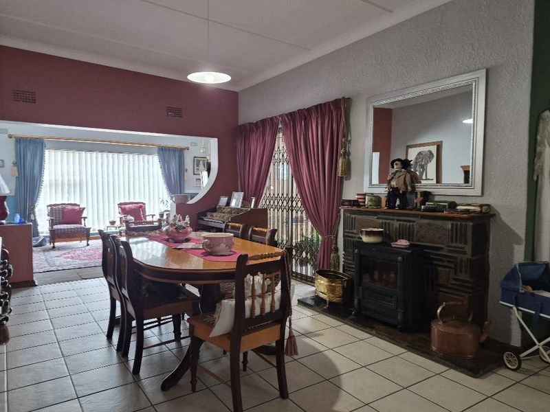 A dining room featuring tiled flooring, a built-in fireplace, and an open-plan layout connecting to an adjacent living area.