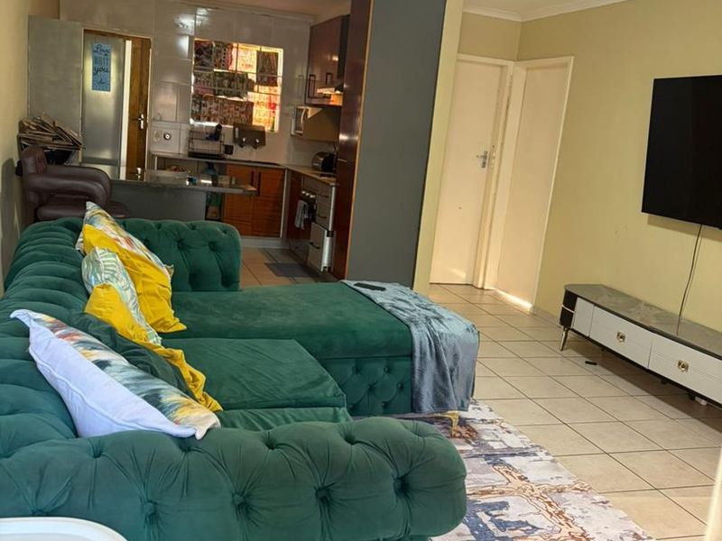 Open plan living area featuring tiled flooring and a compact kitchen with built-in cabinetry, creating a functional combined living and cooking space.